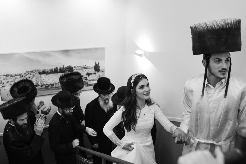 החתן והכלה בצילום שחור לבן אומנותי בדרכם לחדר ייחוד