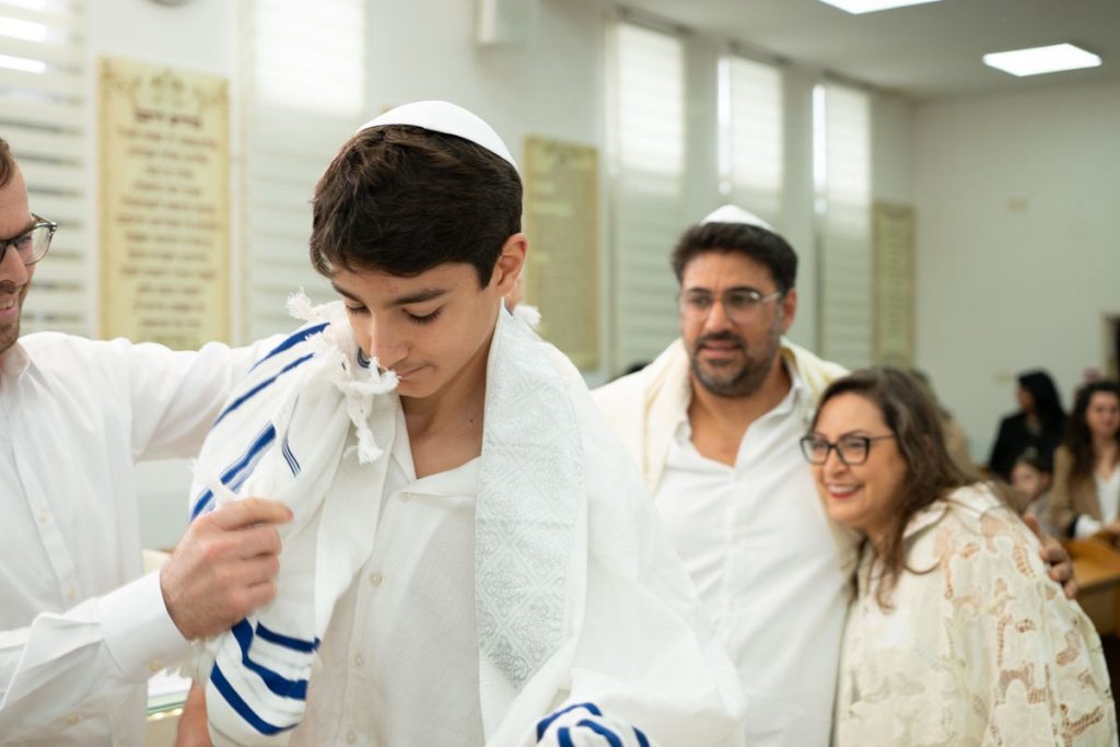 נער בר מצווה מתעטף בטלית בבית כנסת, צילום תקריב.