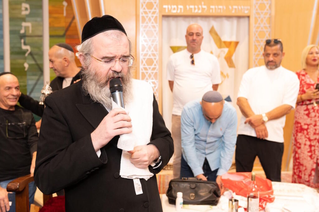 רב מברך במיקרופון בטקס ברית מילה בבית כנסת