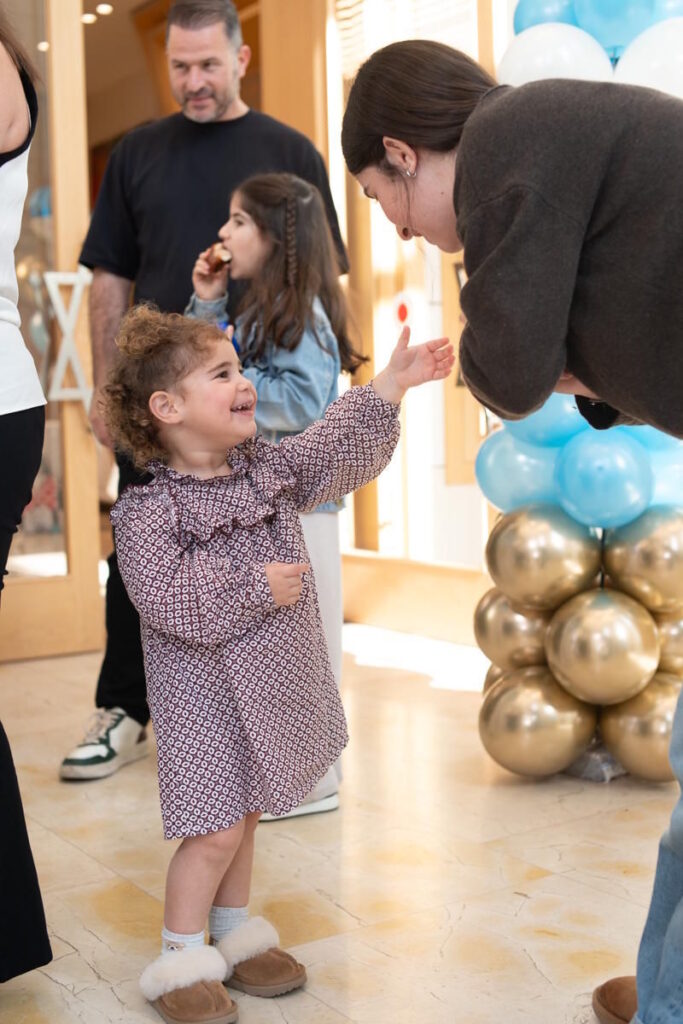 ילדה מחייכת בטקס ברית מילה בבית כנסת