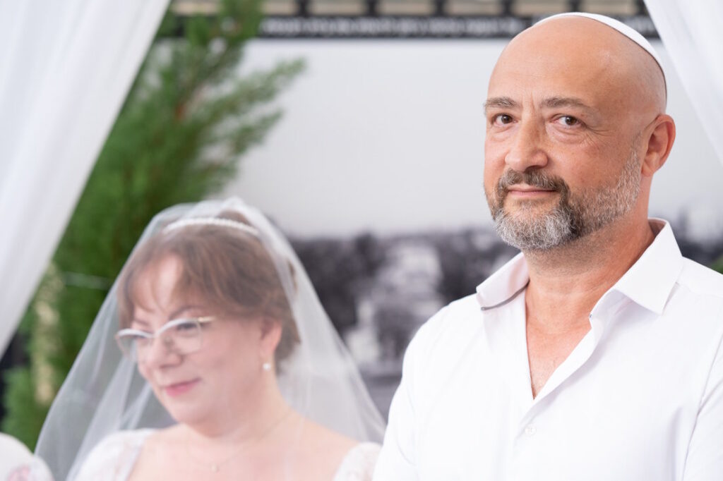 החתן מביט בכלתו מתחת לחופה בחתונה קטנה ברחובות