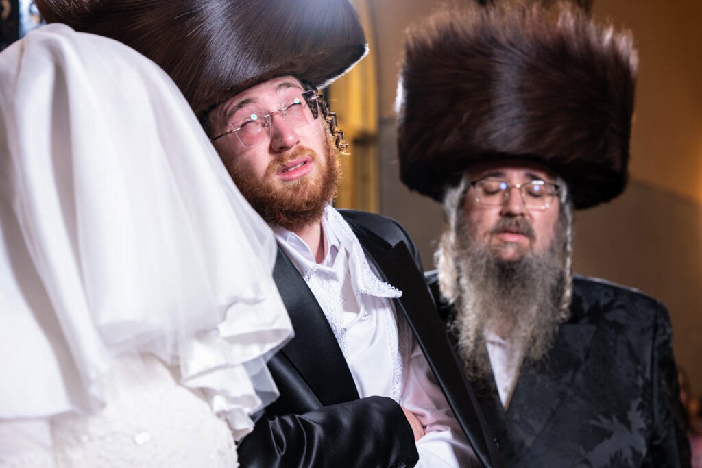 חתן חסידי תחת החופה ברגע מרגש, צלם חתונות דתי המתמחה ברגעים אותנטיים.
