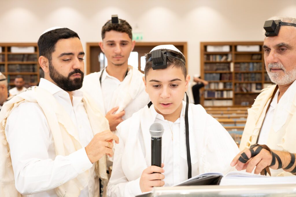צילום הנחת תפילין ובר מצווה בבית כנסת, נער קורא בסידור