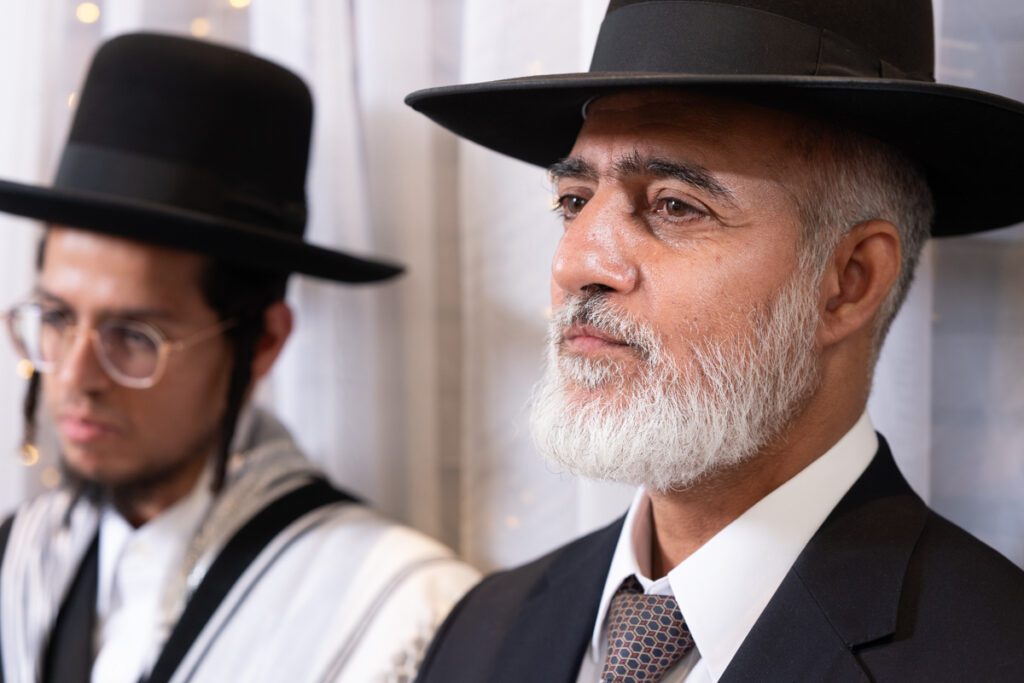 גבר חרדי עם זקן לבן וכובע חסידי מביט בהתרגשות במהלך חתונה חרדית, צילום חתונות חרדיות מקצועי.