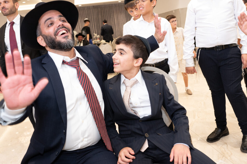 חתן בר המצווה ואביו ברגע מרגש ומחייך במהלך אירוע בר מצווה באלעד