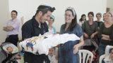 רגע לפני טקס הברית האמא המאושרת מקבלת את התינוק מהסנדק - צלמים לציבור הדתי